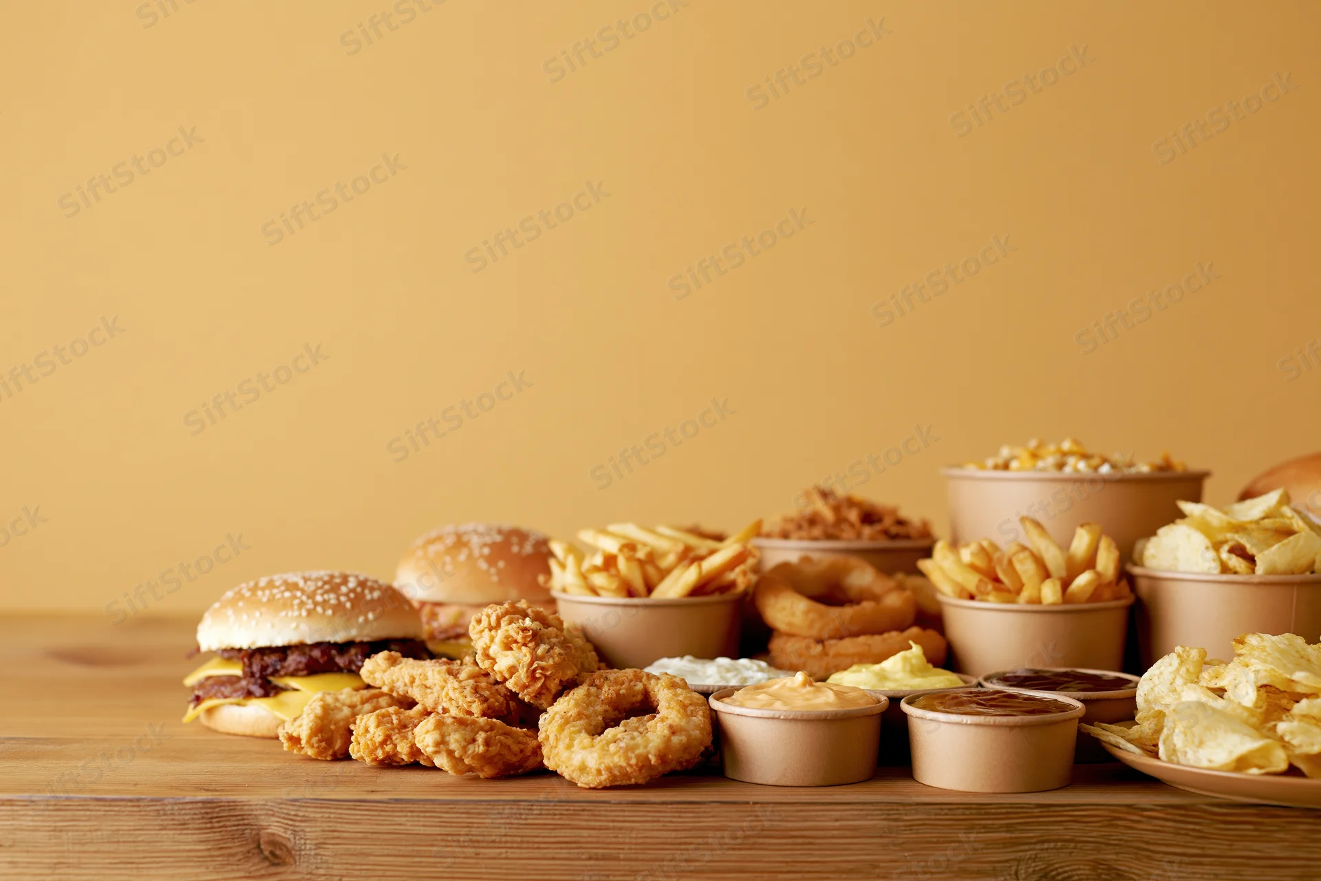 Assorted fast food items arranged on a wooden table with copyspace on the left