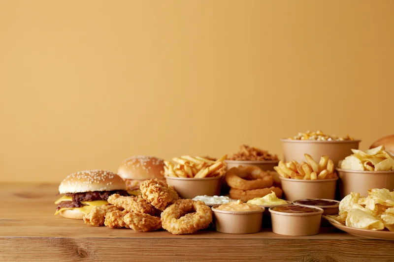 Assorted fast food items arranged on a wooden table with copyspace on the left