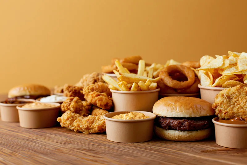 Assorted fast food items arranged on a wooden table with copyspace on the left
