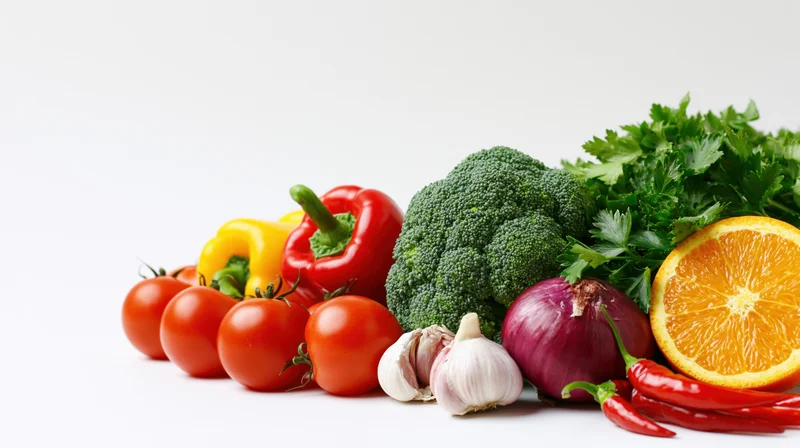 Assorted fresh vegetables and fruit arranged in a low horizon on white background