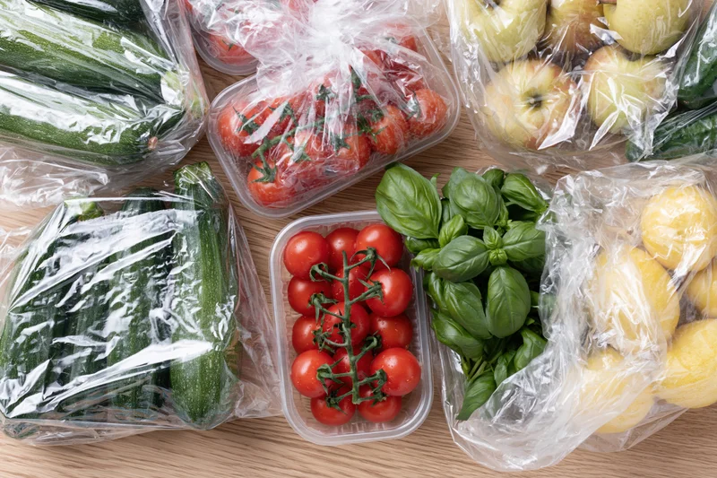 Fresh vegetables and fruits in plastic packaging on a wooden countertop