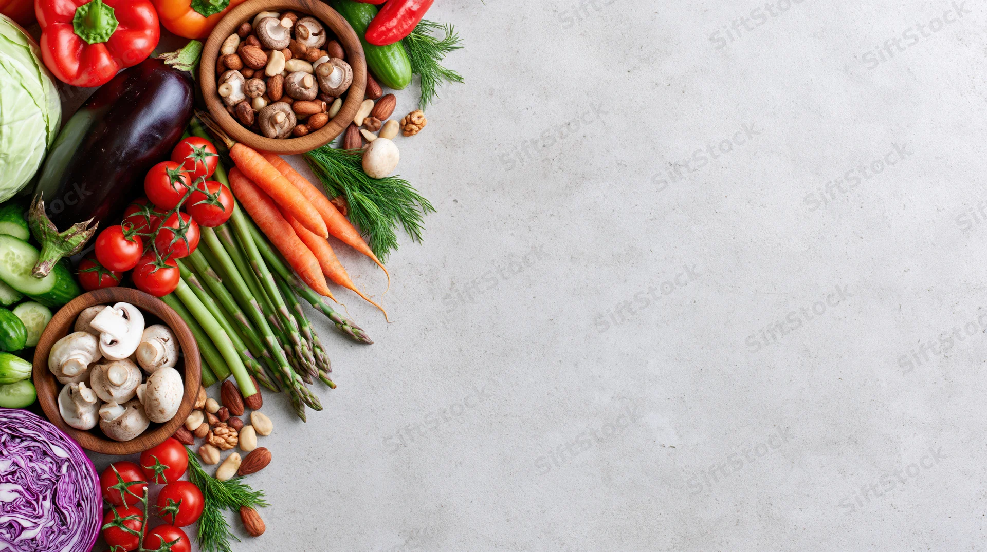 Fresh vegetables and nuts arranged along the left edge of a light countertop with copyspace