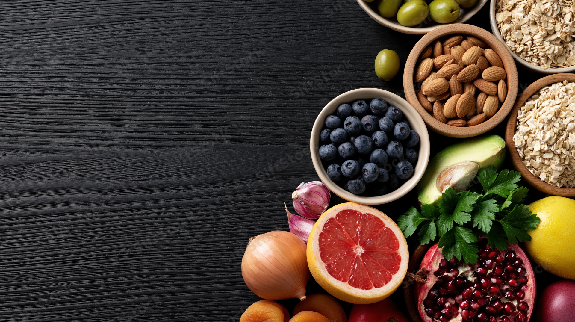 Healthy foods arranged on dark wooden table with copyspace on left