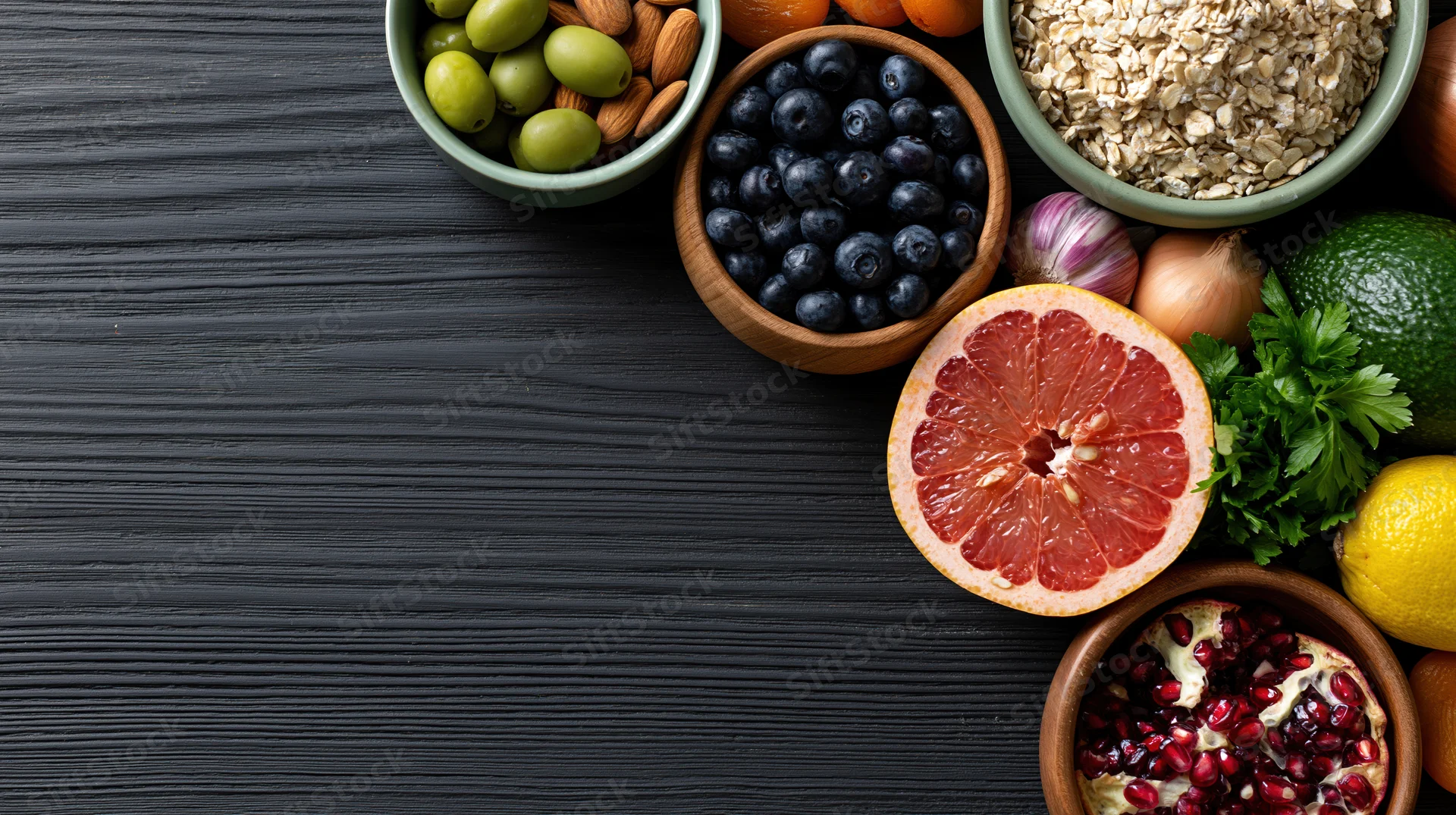 Assorted healthy foods arranged on dark wooden table with copyspace on left