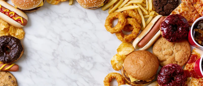 Assorted fast food items arranged in a border around a marble surface with copyspace in center