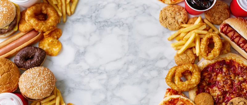 Assorted fast food items arranged in a border around a marble countertop with central copyspace