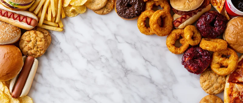 Assorted fast food items arranged in a border around a marble surface with copyspace in center