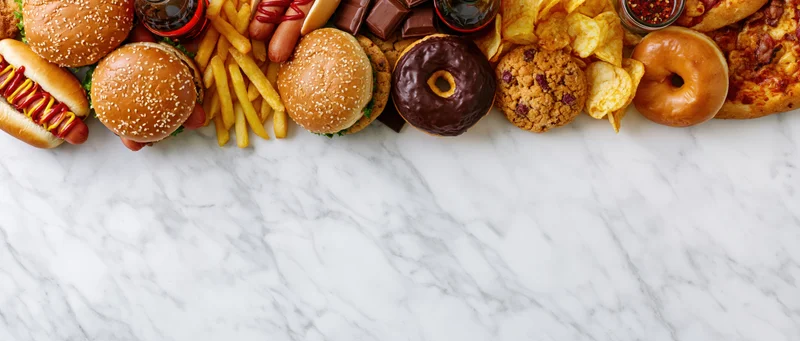 Assorted fast food items arranged in a row on a marble surface with copyspace below