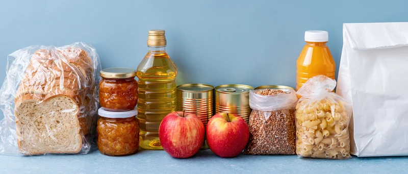 Assorted nonperishable food items arranged in a row on a blue surface