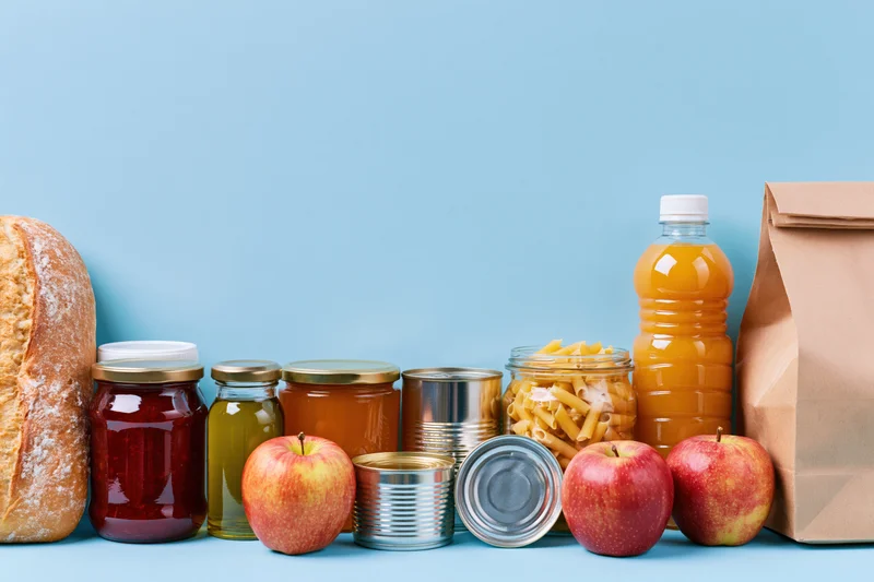 Assorted pantry staples and grocery items arranged in a row on a blue surface