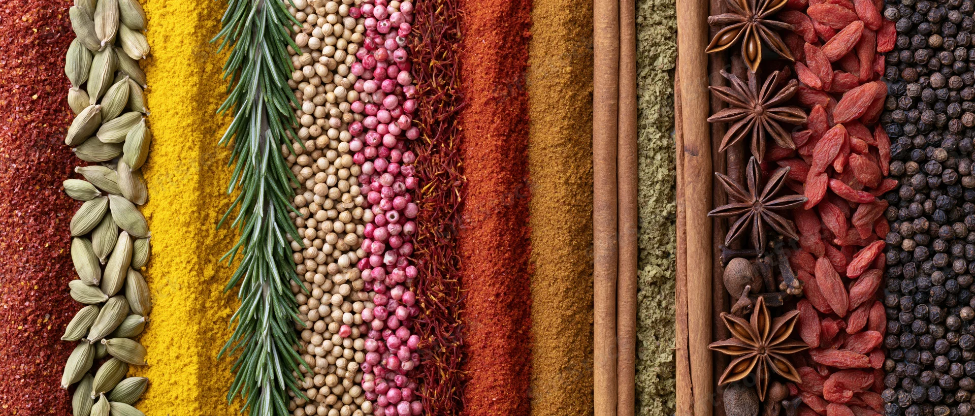 Vertical stripes of assorted whole and ground spices arranged in a row