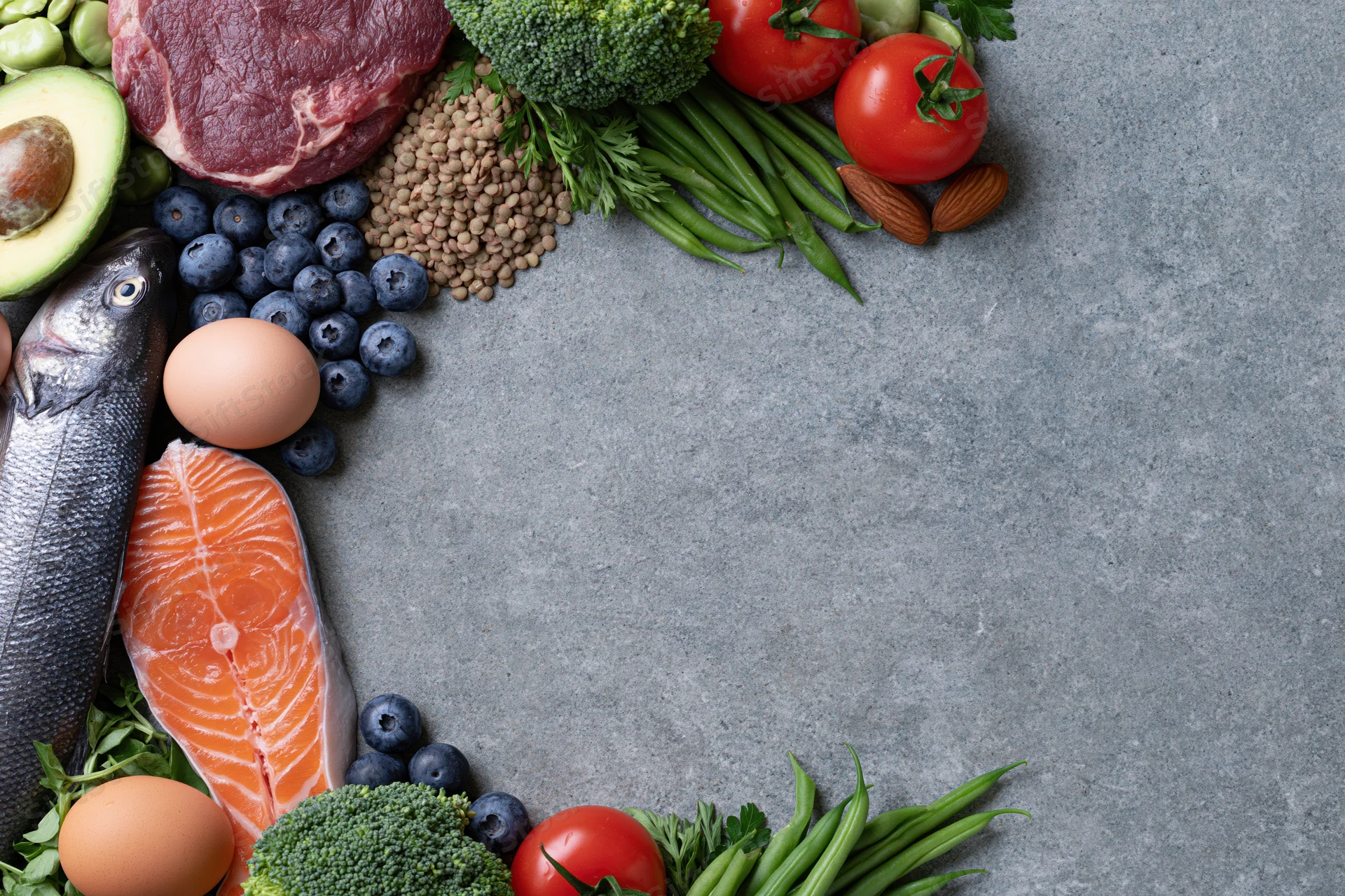 Assorted whole foods arranged in a circular frame on a slate countertop with copyspace