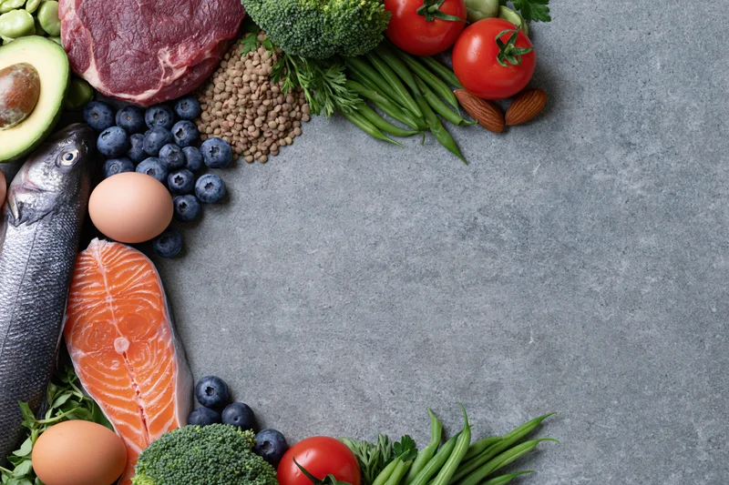 Assorted whole foods arranged in a circular frame on a slate countertop with copyspace