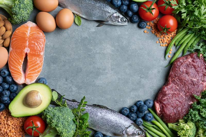Assorted whole foods arranged in a circular frame on a slate surface with copyspace in center