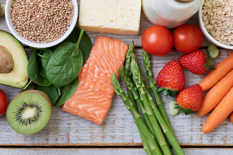 Salmon fillet and assorted whole foods arranged in flat lay on wooden surface