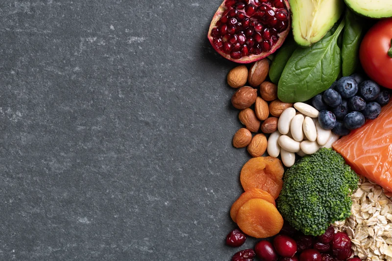 Healthy whole foods arranged along the right edge on dark slate surface