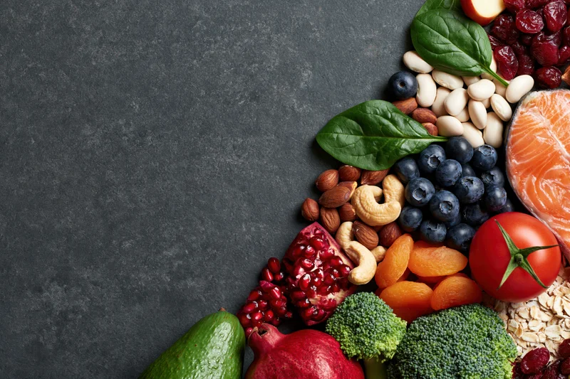 Healthy whole foods arranged along the right edge on dark stone surface