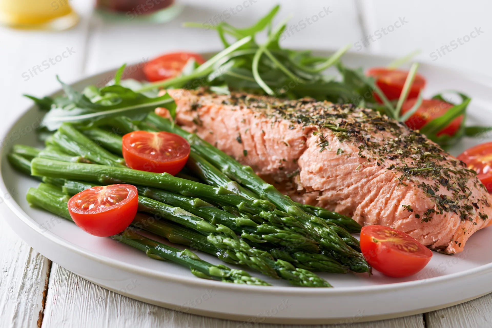 Baked salmon fillet with asparagus and cherry tomatoes on a white plate