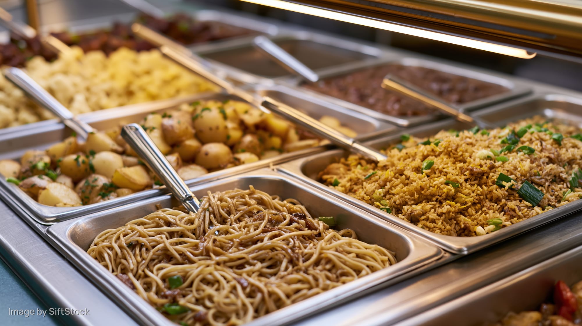 Stainless steel hotel pans filled with various dishes arranged in a cafeteria buffet line