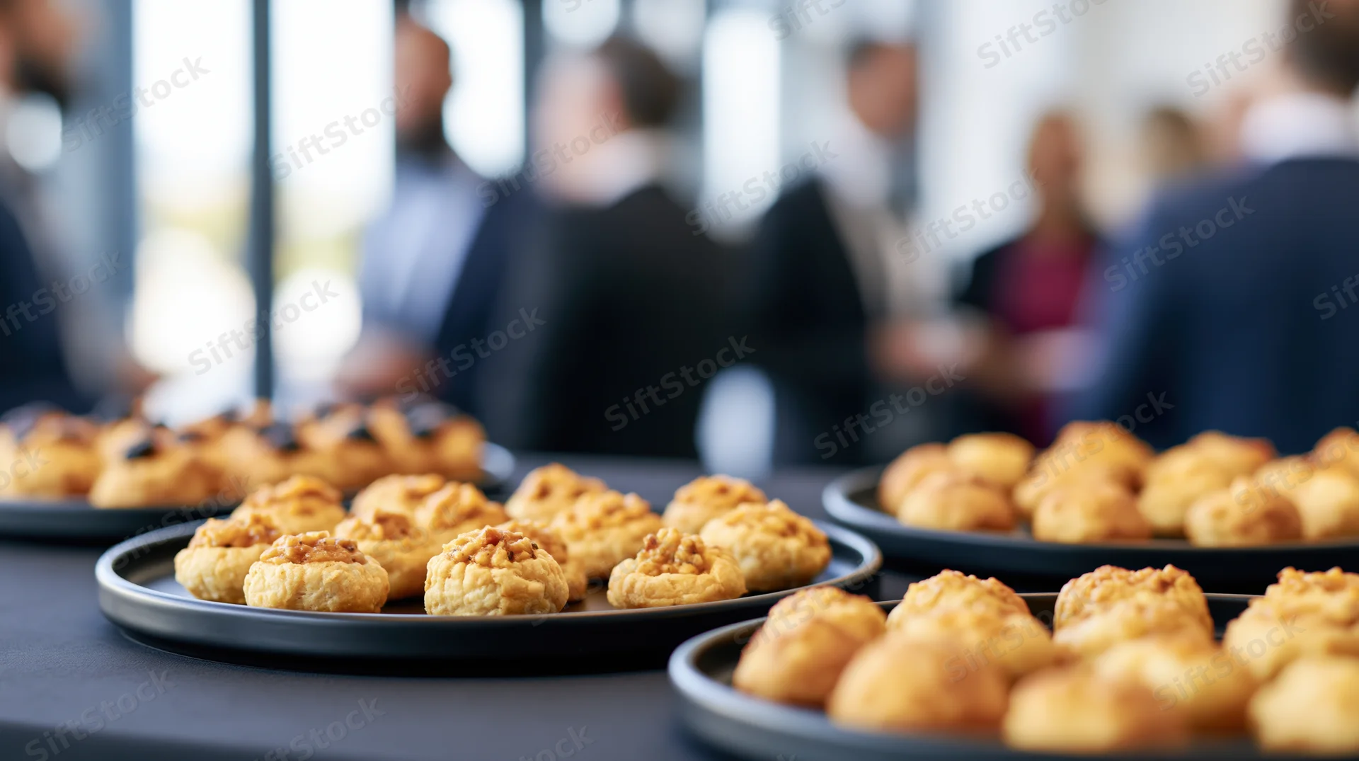 Golden baked canapes arranged on black trays at a corporate event reception