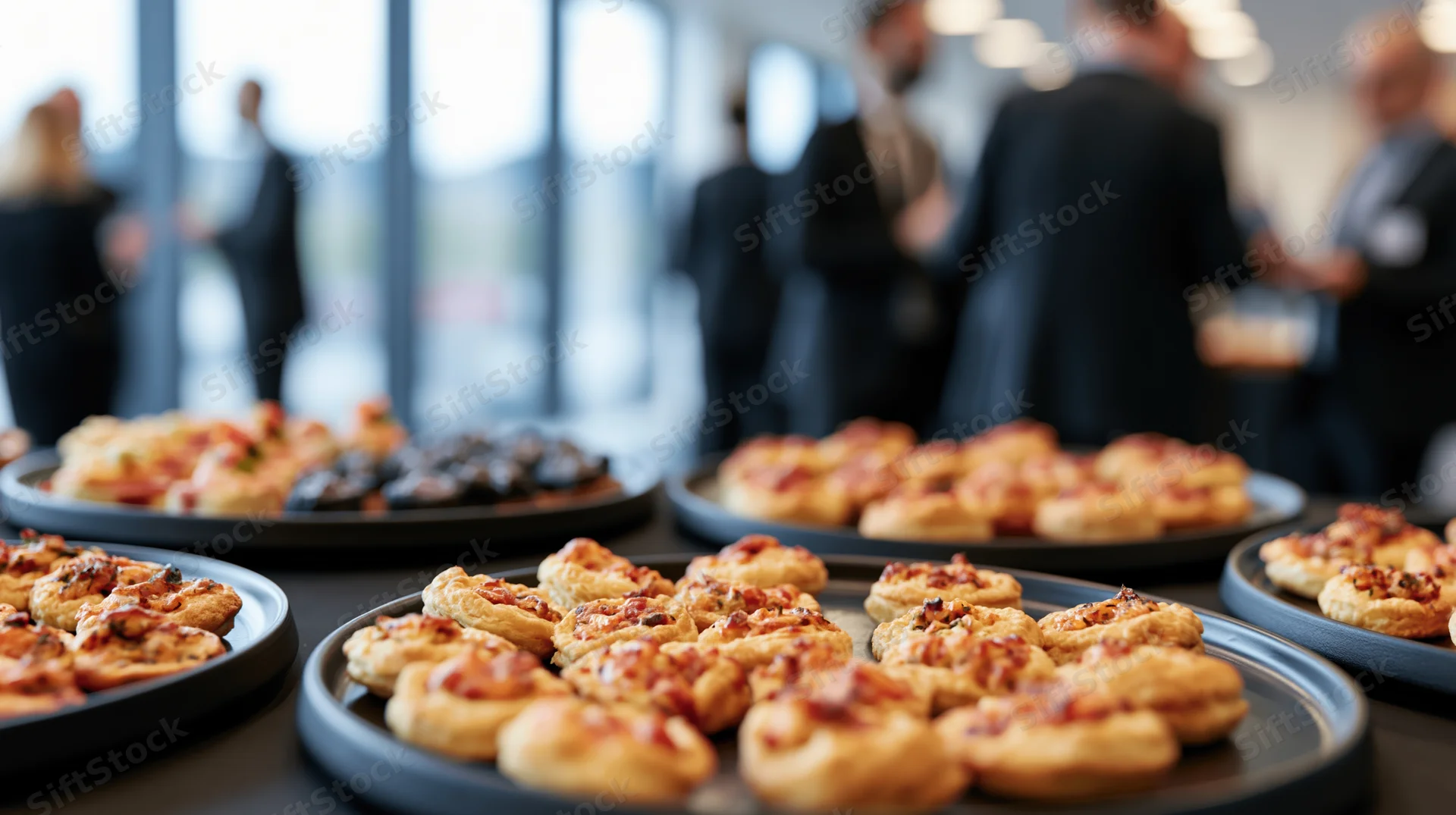 Small appetizers arranged on round black trays at a corporate event reception