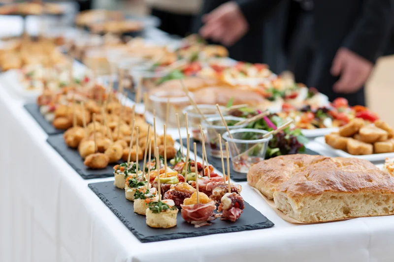 Buffet table with assorted finger foods and appetizers arranged on slate trays and plates for an event reception