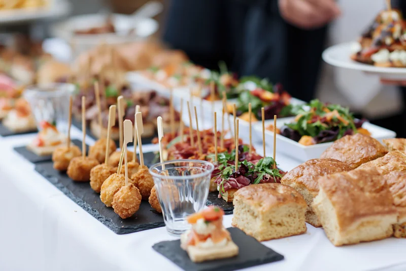 Buffet table with assorted finger foods and appetizers arranged on slate trays and glassware for an event reception