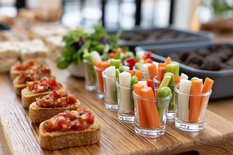 Canapes and crudite in shot glasses arranged on a wooden board for a party buffet