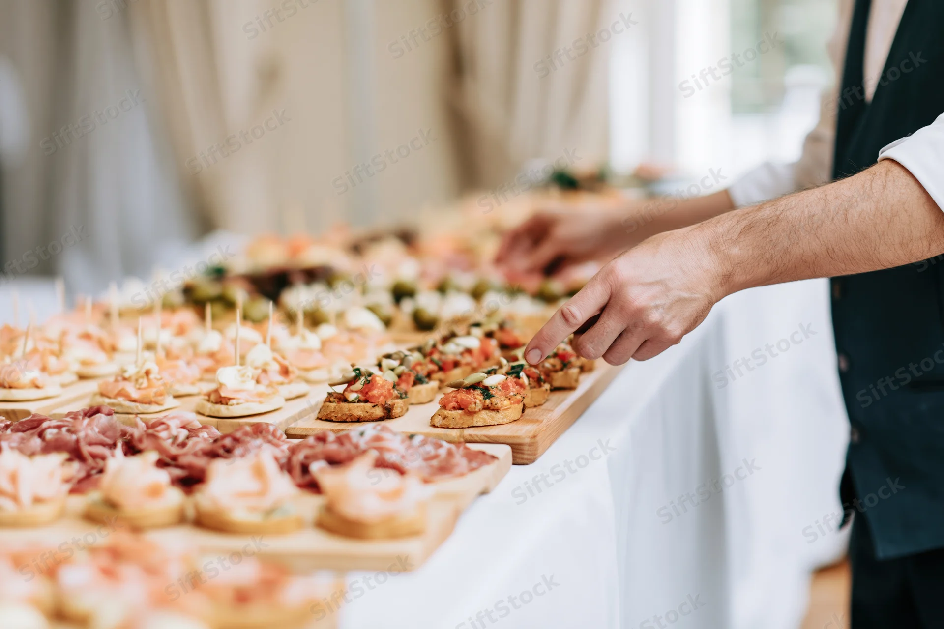 Man arranging small appetizers on a buffet table at a wedding reception