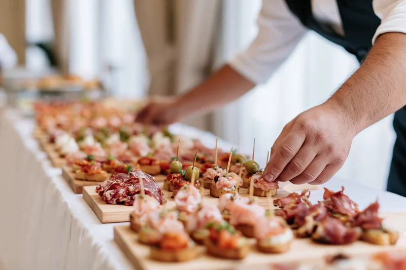Man arranging small appetizers on wooden boards at a buffet table