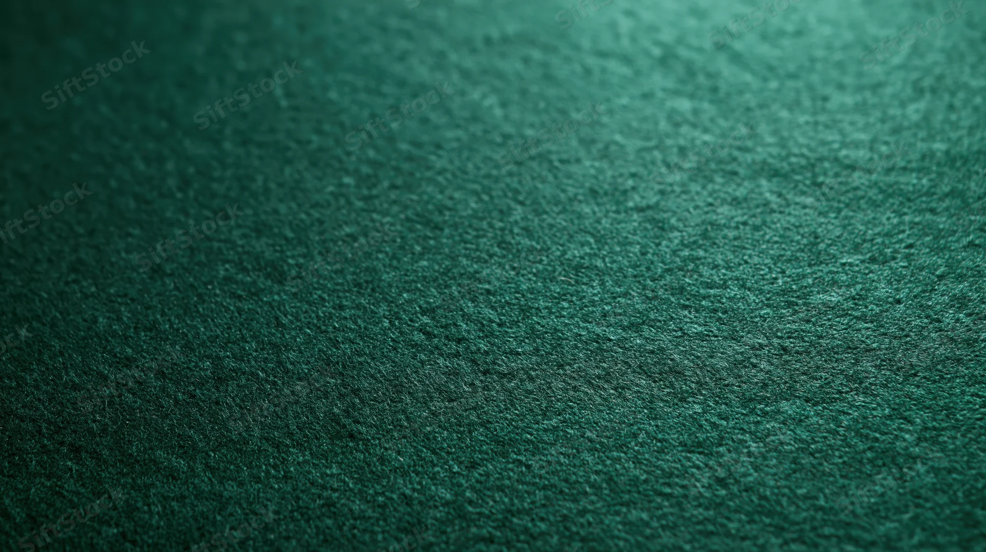 Close-up of deep emerald green felt fabric with textured surface and soft lighting