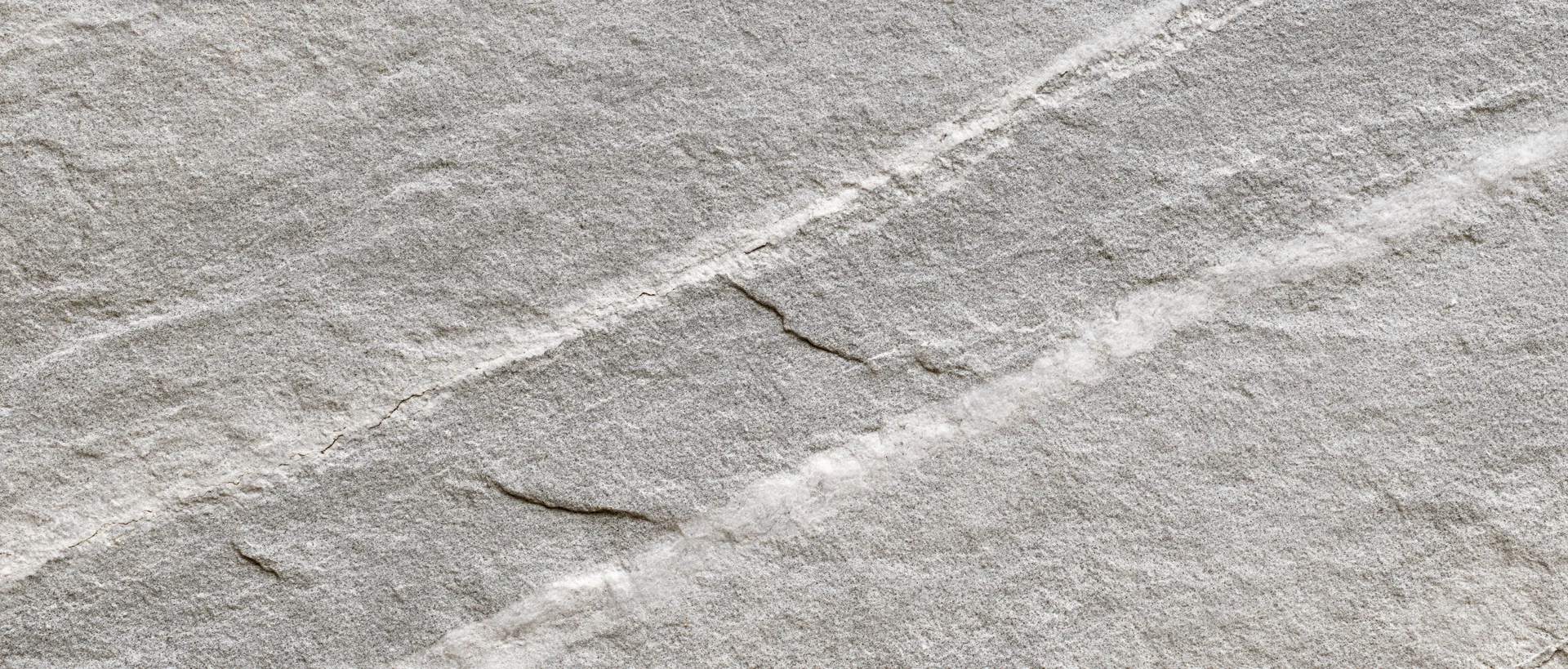 Close-up of natural grey stone surface with visible cracks and veins