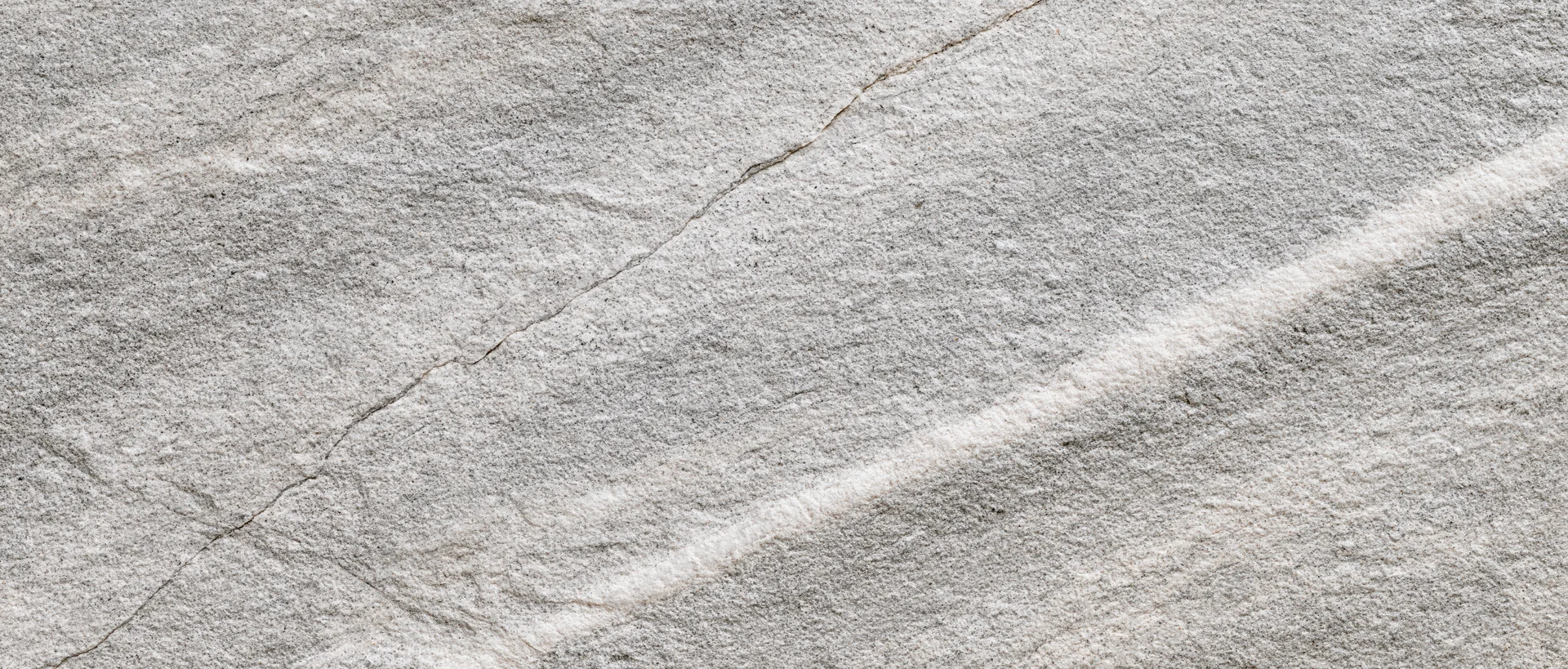 Close-up of natural grey stone surface with cracks and veins filling the frame