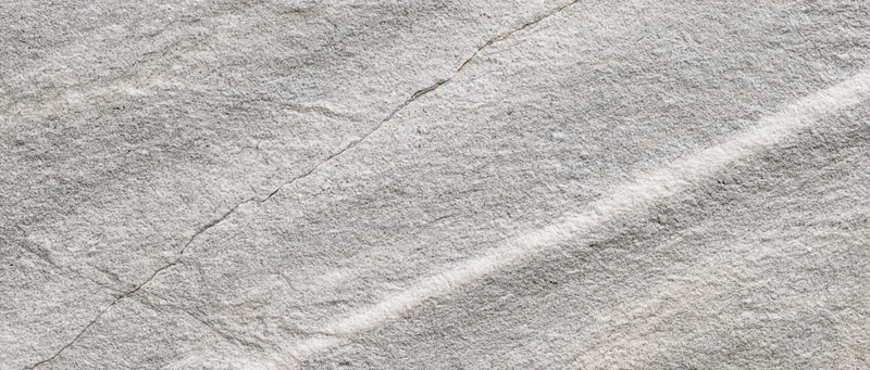 Close-up of natural grey stone surface with cracks and veins filling the frame