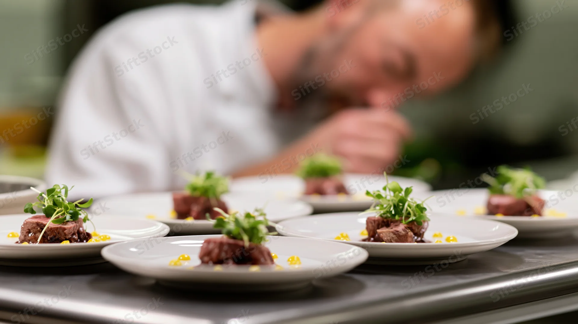 Chef plating gourmet dishes on white porcelain plates in a restaurant kitchen