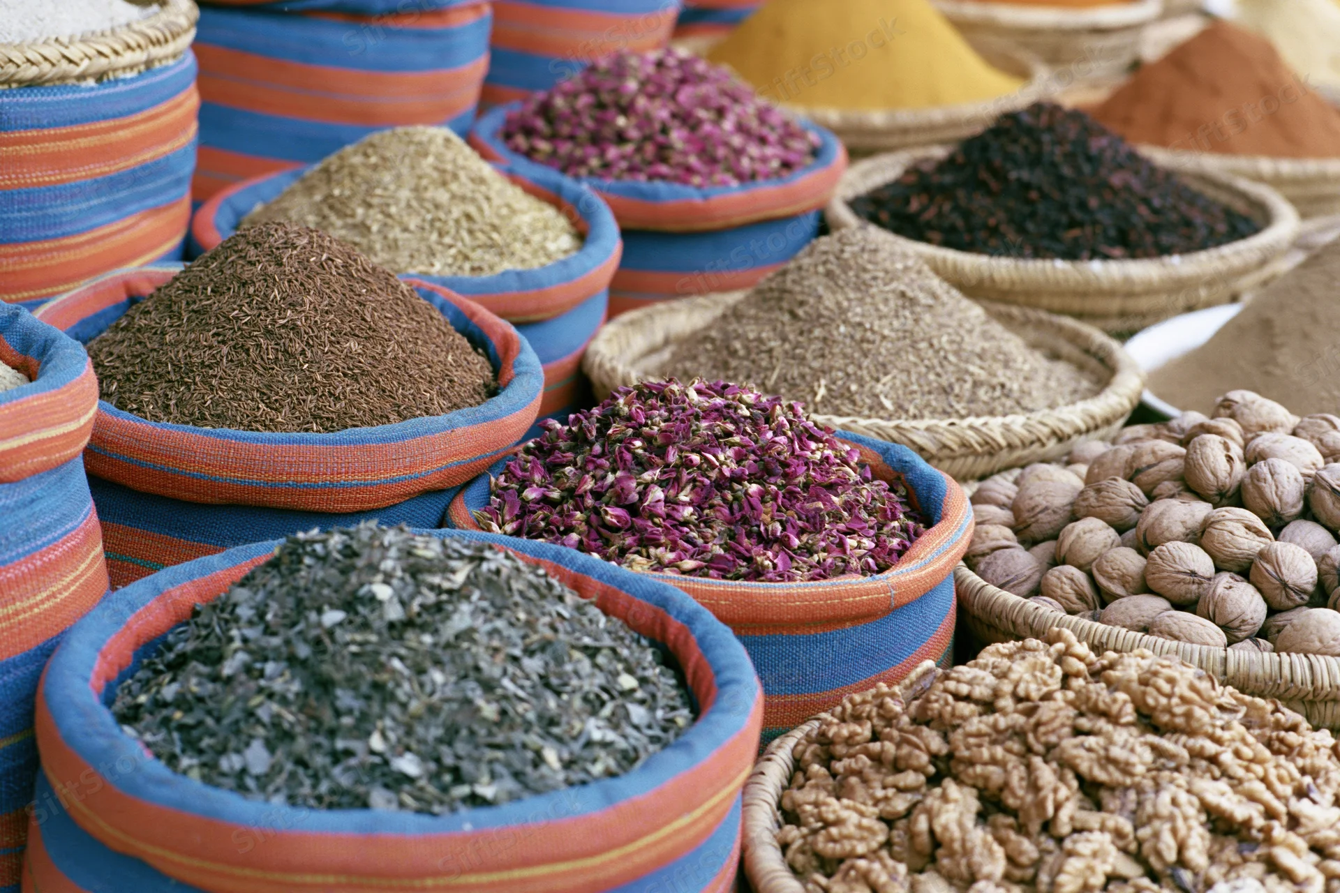 Colorful woven baskets and bowls filled with dried spices and nuts arranged in a market display
