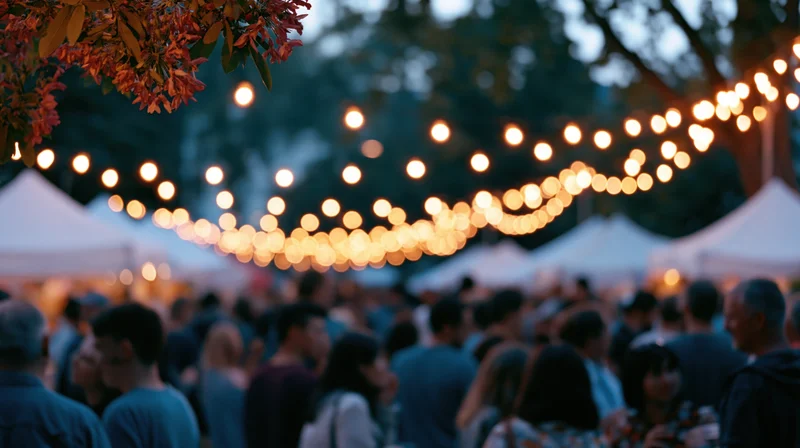 Crowd mingling at outdoor evening festival under string lights and tents