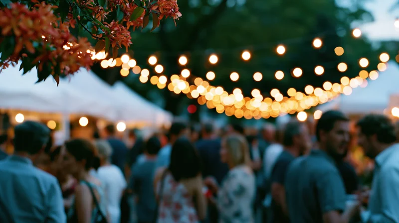 Crowd of people mingling at an outdoor evening festival under string lights and tents