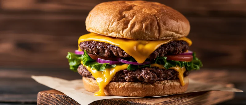 Double cheeseburger with two beef patties and melted american cheese on a wooden board
