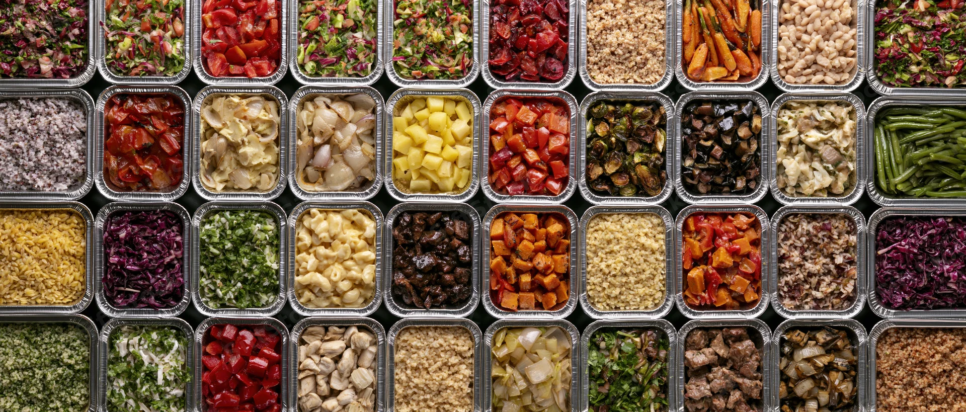 Dozens of aluminum foil takeout containers arranged in a grid, filled with various chopped vegetables, grains, and