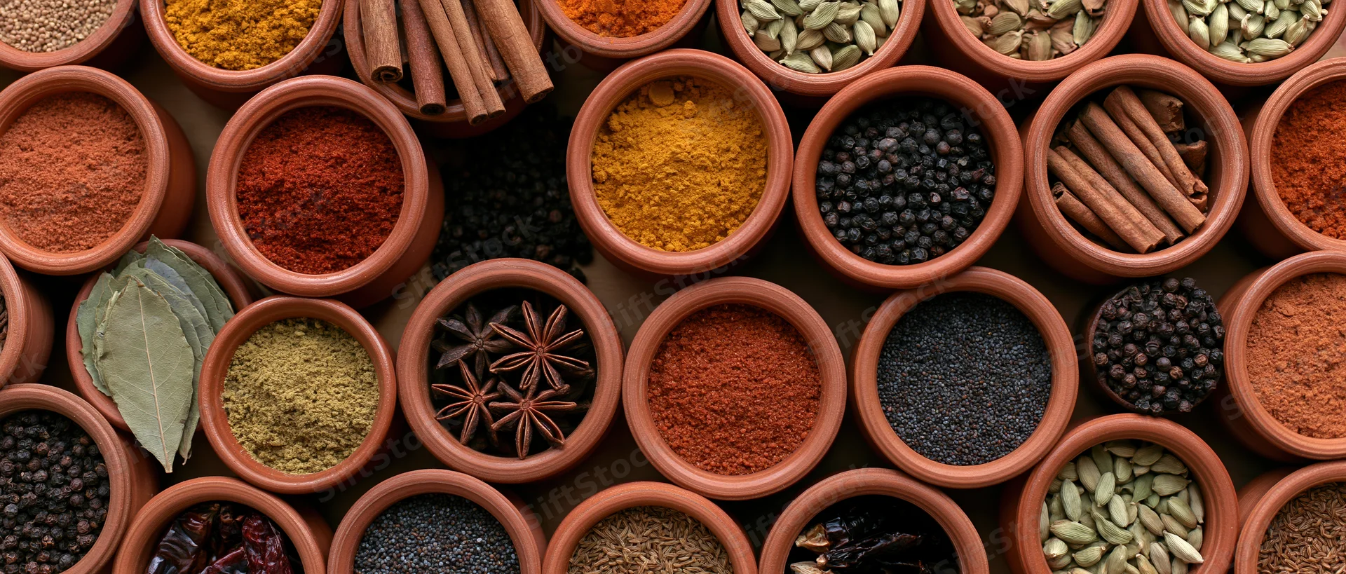 Terracotta bowls filled with various spices arranged in a tight grid pattern