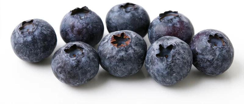 Fresh blueberries scattered on a white surface