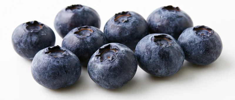 Fresh blueberries scattered on a white surface