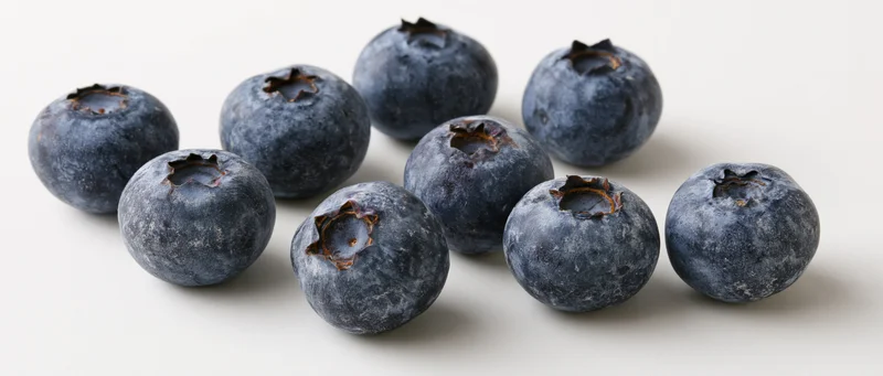 Fresh blueberries scattered on a white surface