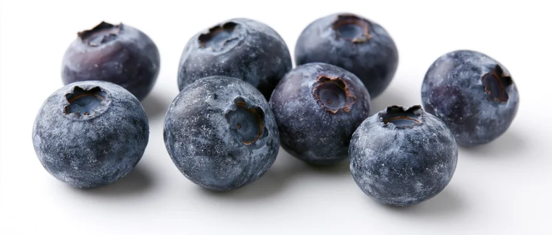 Fresh blueberries scattered on a white surface