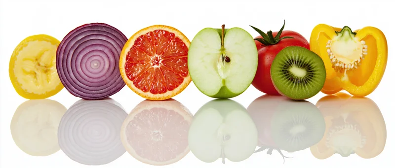 Row of sliced fruits and vegetables on reflective white surface