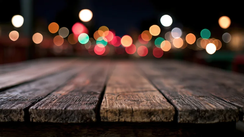 Weathered wooden table surface in foreground with blurred city lights at night