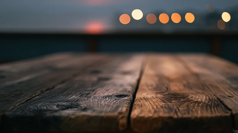 Rustic wooden tabletop in foreground with blurred city lights in background at twilight
