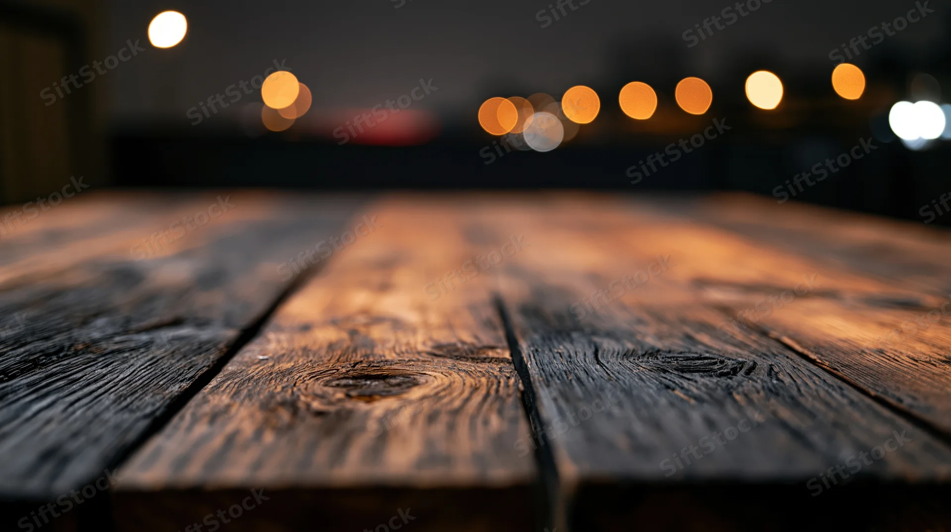 Low-angle view of empty rustic wooden tabletop with blurred lights in background