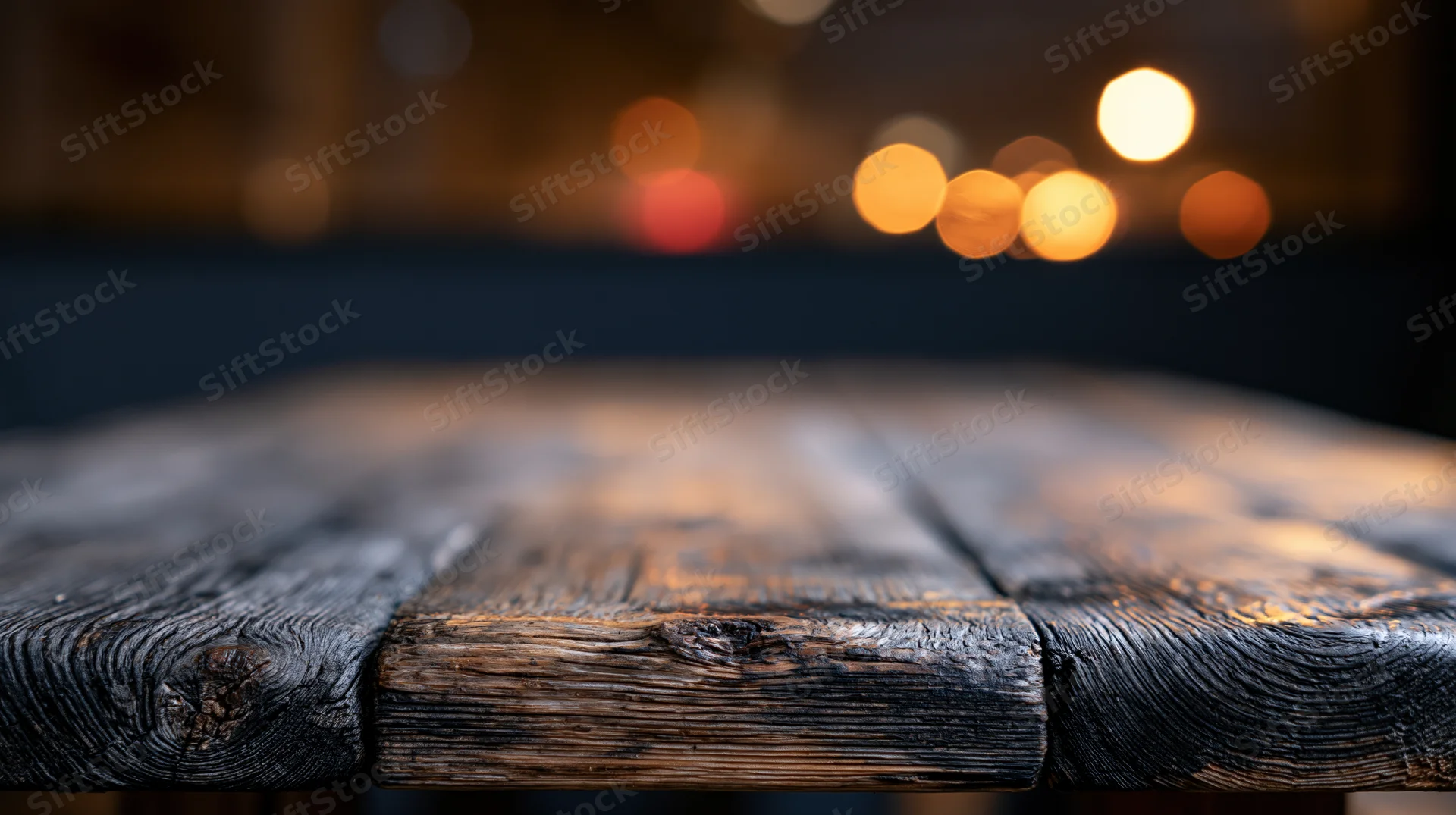 Rustic wooden table surface in foreground with blurred warm lights in background